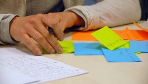 Eine Hand mit Stift, die auf Papier und Haftnotizen schreibt